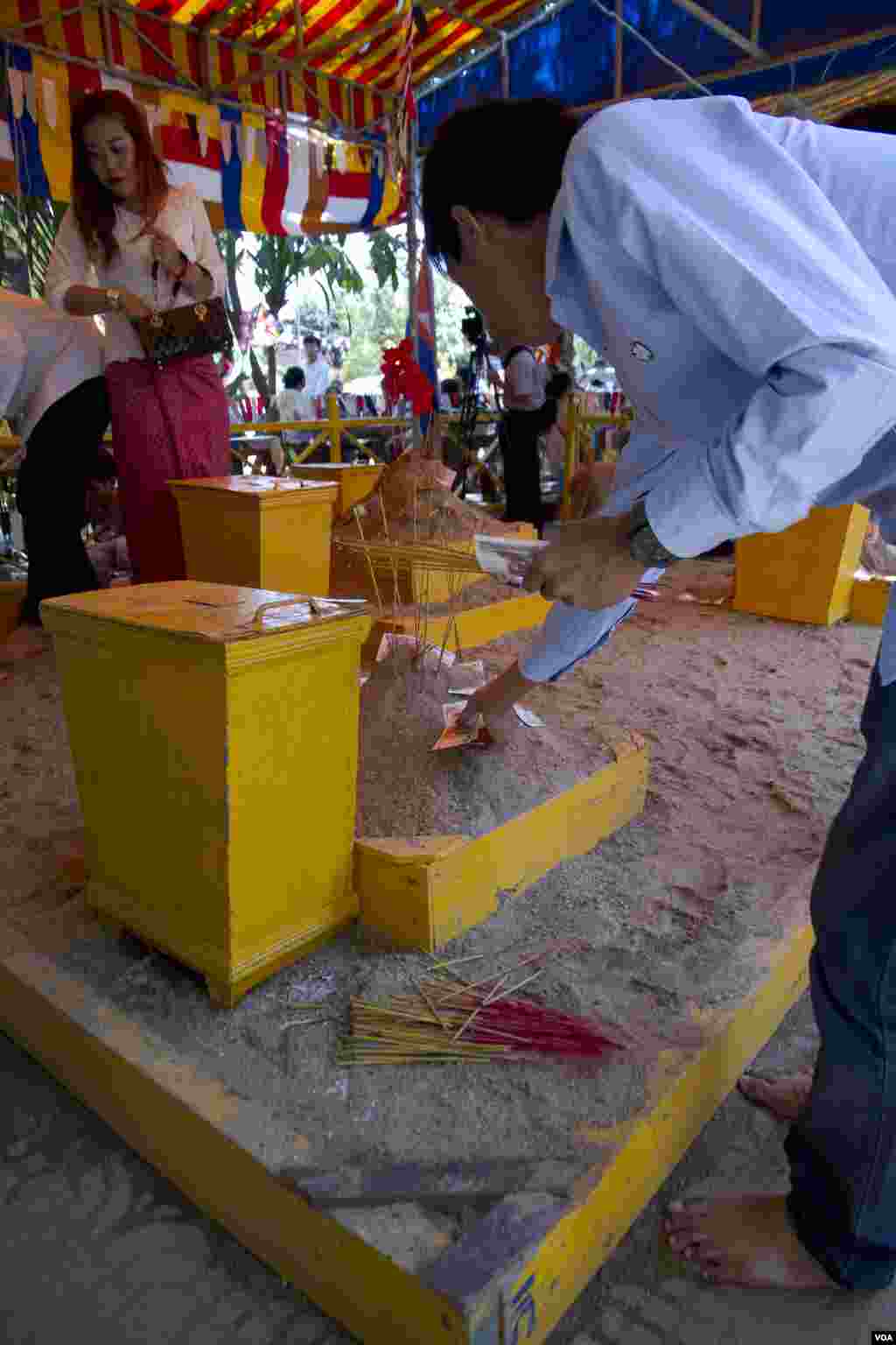 បុរសម្នាក់ដាក់បច្ច័យជាប្រាក់នៅលើភ្នំខ្សាច់នៅវត្តឧណ្ណាឡោម ក្នុងពេលបុណ្យចូលឆ្នាំខ្មែរនៅថ្ងៃអង្គារ។