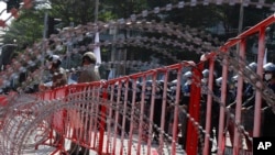 Police stand a guard behind razor wire during a demonstration near the Asia-Pacific Economic Cooperation (APEC) forum venue, Nov. 17, 2022, in Bangkok.