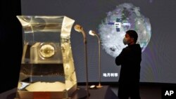 一位參觀者正在中國國家博物館觀看嫦娥5號探月火箭2021年3月12號從月球採集到的新岩石樣本。中國宣佈他們在月球岩石中發現了一種新物質,取名叫“嫦娥石”。(美聯社照片)