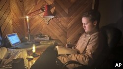 Danylo, de 17 años, asiste a una clase online de biología a la luz de las velas en la localidad de Start Petrivtsi, cerca de Ucrania, el 3 de noviembre de 2022. (AP Foto/Efrem Lukatsky)