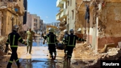 Timu ya waokoaji kutoka jeshi la Misri wakibeba miili wakipita katikati ya majengo yaliyoharibiwa na kimbunga na mvua kubwa zilizoikumba Libya, huko Derna, Sept. 13, 2023.