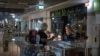 A seller shines a flashlight as she shows goods to a customer during a power outage in Kyiv, June 19, 2024. Russian regular massive missile attacks against Ukraine's energy facilities have resulted in electricity supply restrictions.