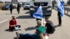FILE - Israeli protesters block the road to Jordanian trucks carrying humanitarian aid supplies arriving on the Israeli side of the Kerem Shalom border crossing with the Gaza Strip in southern Israel on April 16, 2024.