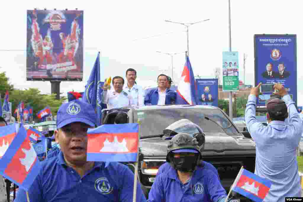 លោក យ៉ែម បុញ្ញប្ញទ្ធិ (ឆ្វេង) និង លោក ញឹក ប៊ុនឆៃ (ស្តាំ) ដឹកនាំអ្នកគាំទ្រគណបក្សគណបក្សខ្មែររួបរួមជាតិរបស់ខ្លូននៅការហែក្បួនយុទ្ធនាការឃោសនាបោះឆ្តោតនៅរាជធានីភ្នំពេញ ថ្ងៃទី១ ខែកក្កដា ឆ្នាំ២០២៣។ (លាស់ លីបលីប/វីអូអេ)