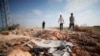 Palestinian men walk towards a crater and debris caused by an improvised explosive device which targeted an Israeli military jeep, in the northern Palestinian city of Jenin, in the Israeli occupied West Bank on June 27, 2024.