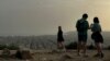 FILE - Tourists visit the Filopappou Hill, as Greece is hit by high temperatures and Saharan dust due to southern winds, in Athens, Greece, April 2, 2024.