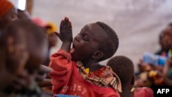 Mtoto Kevin, ambaye ni mkimbizi akiulamba mkono wake akifurahia chakula huko Nyabitara Transit, Burundi. Tarehe 3 Oktoba 2019. Picha na TCHANDROU NITANGA / AFP.