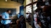 An election official checks the identity cards of people who are waiting to vote in the Democratic Republic of the Congo's parliamentary and presidential elections, in Kinshasa, Dec. 21, 2023. 