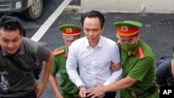 FILE - Trinh Van Quyet, a prominent Vietnamese business tycoon, is escorted to a court for his trial of defrauding stockholders, in Hanoi, July 22, 2024. 