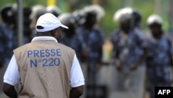 Un journaliste face aux forces de sécurité empêchant une foule d'approcher le Palais des Congrès à Lomé, au Togo, le 19 février 2013. (AFP)
