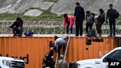 Maafisa wa Forodha na Ulinzi wa Mipaka wa Marekani wakimchukua mtoto wa mhamiaji kutoka kwa mama yake baada ya kuvuka mpaka huko Eagle Pass, Texas Desemba 22, 2023. Picha na AFP 