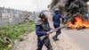 Democratic Republic of Congo police officers stand next to a burning barricade during an opposition demonstration in Kinshasa, Dec. 27, 2023. Police were deployed in the capital Kinshasa during a banned demonstration against recent elections.