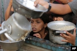A Palestinian boy waits for his portion of food aid ahead of the upcoming Eid al-Adha holiday in Jerusalem, June 15, 2024.