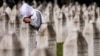 A Bosnian Muslim woman mourns next to the grave of her relative, a victim of the Srebrenica genocide, at the Srebrenica Memorial Centre, in Potocari, Bosnia, July 11, 2024. 