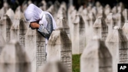 A Bosnian Muslim woman mourns next to the grave of her relative, a victim of the Srebrenica genocide, at the Srebrenica Memorial Centre, in Potocari, Bosnia, July 11, 2024. 