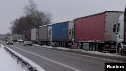 FILE - Trucks line up in a long queue to cross the Polish-Ukrainian border at the Dorohusk-Jagodzin crossing, in Okopy, Poland, Dec. 4, 2023.