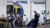 A police officer throws a rock as opposition supporters run into the house of opposition leader Martin Fayulu during a demonstration in Kinshasa, Congo, Dec. 27, 2023.