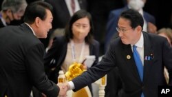 資料照：日本首相岸田文雄（右）與南韓總統尹錫悅在柬埔寨出席東盟峰會期間握手。（2022年11月13日）