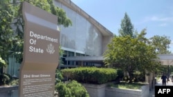 FILE — Signage is seen outside one of the entrances of the U.S. Department of State in Washington, Aug. 6, 2021. 