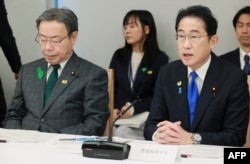 日本首相岸田文雄在星期五一場政策會議上講話，日本國家公安委員長谷公一（左）坐在他身旁。（2023年4月28日）