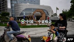 中國西安市民路過街頭豎立的中亞峰會宣傳牌。（法新社2023年5月17日）