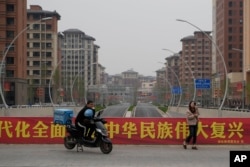 中國河北雄安街頭一名快遞小哥在口號橫幅前休息。 （2023年4月1日）