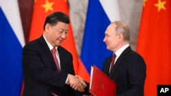2023 年 3 月 21 日，俄羅斯莫斯科克里姆林宮，俄羅斯總統弗拉基米爾·普京（右）和中國國家主席習近平在會談後的簽字儀式上握手交換文件。