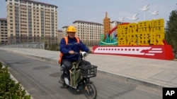 中國河北雄安街頭一名工人騎車路過一處口號宣傳牌。 （2023年4月1日）