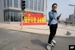 中國河北雄安街頭一名男子路過一處口號宣傳牌。 （2023年4月1日）