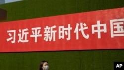 一名女子從北京街頭張貼的一條宣傳習近平新時代的標語下走過。 （2019年9月27日）