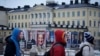 People walk by election posters with the Presidential Palace in the background, in Helsinki, Finland, Jan. 27, 2024, ahead of the Finnish presidential election on Jan. 28.