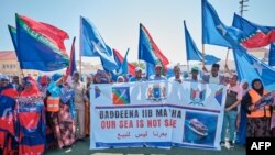 Des manifestants brandissent des bannières et des drapeaux lors d'une manifestation de soutien au gouvernement somalien suite à l'accord portuaire entre l'Éthiopie et la région séparatiste du Somaliland, le 3 janvier 2024. AFP / Abdishukri Haybe