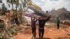 Watu wawili wakibeba magodoro baada ya mlima wa taka kuporomoka mjini Kampala, Agosti 10, 2024. Picha ya AFP