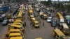 Commuters walk next to parked public transport mini buses at Ojodu Berger bus station in Lagos, on June 1, 2023. Nigerians are lamenting the effect removal of the fuel subsidy is having on the economy, especially the massive hike in transport fare and cost of goods and services. 