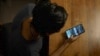 FILE - Sagaing exile looks down at his Iphone at a 'safe house' near the Thai-Myanmar border, to check the latest updates on Burmese army attacks in his home region, one of the hardest hit areas in Myanmar, July 22, 2022. (Steve Sandford/VOA)