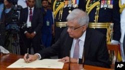 2022年7月21日，斯里蘭卡新當選總統拉尼爾·維克勒馬辛哈（Ranil Wickremesinghe）在科倫坡宣誓就職後簽字。照片由斯里蘭卡總統辦公室發布，美聯社提供。