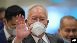 Former Malaysian Prime Minister Najib Razak, center, wearing a face mask arrives at Court of Appeal in Putrajaya, Malaysia, Aug. 16, 2022.
