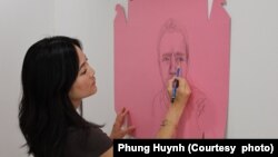 អ្នកស្រី Phung Huynh សិល្បៈករ​ផ្នែក​គំនូរ និង​សាស្ត្រាចារ្យ​ផ្នែក​សិល្បៈ​នៅ​មហា​វិទ្យាល័យ Los Angeles Valley គូរគំនូរនៅលើប្រអប់ខ្ចប់នំដូណាត់ពណ៌ផ្កាឈូក នៅក្នុងស្ទូឌីយោរបស់អ្នកស្រី។ (រូបថតផ្តល់ឲ្យដោយ Phung Huynh)