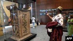 Un homme vêtu d'articles traditionnels prend des photos du trône de cérémonie du roi Ghezo, l'un des objets pillés par les soldats coloniaux français rendus et exposés au grand public lors d'une exposition à la présidence à Cotonou, la capitale du Bénin, le 20 février 2022.