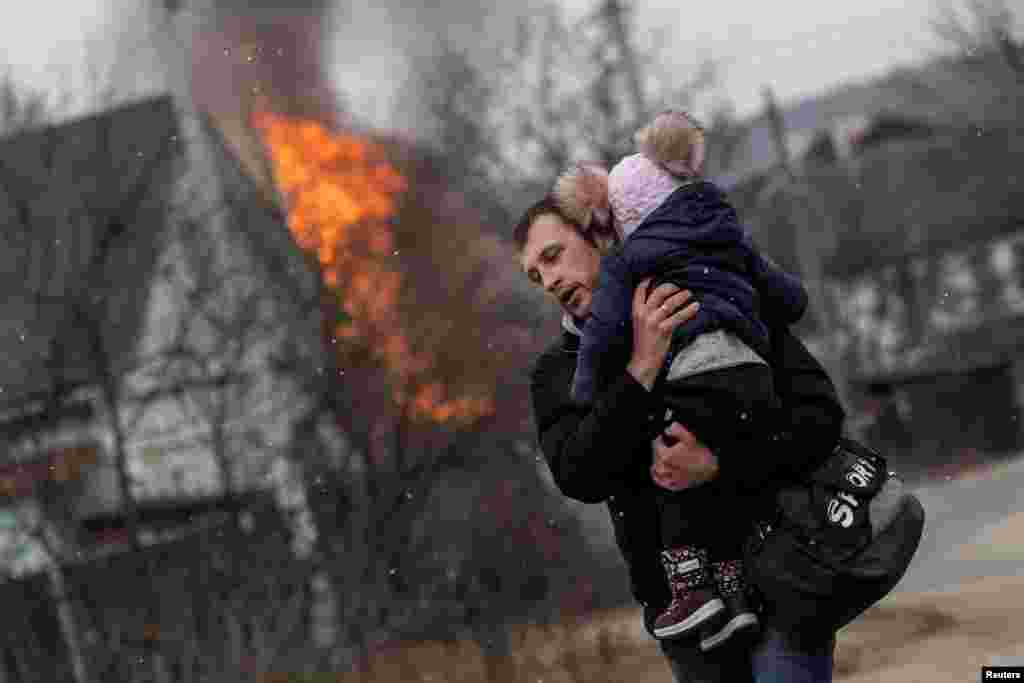 Um homem e uma criança escapam da cidade de Irpin, após bombardeios pesados na única rota de fuga usada por residentes, enquanto tropas russas avançam em direcção à capital, Kyiv, em Irpin, arredores de Kyiv, Ucrânia 6 de Março de 2022