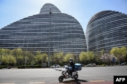 北京一名快遞工人騎著電動車路過一處發現了新冠感染者的辦公樓。 （2022年4月7日）