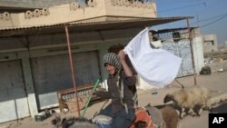 Un homme montre un drapeau blanc alors qu'il s'enfuie d'une zone de conflit à Gogjali, à l'est de Mosul, Irak, le 5 novembre 2016. 