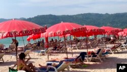 Tourists lounge under umbrellas along Patong Beach in Phuket, Thailand, March 11, 2022. 