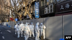 身穿防護服的工作人員在上海一處因發現新冠疫情而被封閉的小區的屏障外。（2022年3月15日）