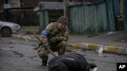 烏克蘭軍人在基輔郊區之前被俄羅斯軍隊佔領的地區檢查死難平民身上是否有誘殺裝置（2022年4月2日）
