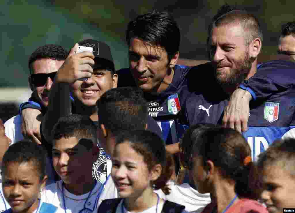 Les footballeurs italiens Gianluigi Buffon et Daniele De Rossi posent pour un selfie avec un enfant au centre d'entraînement de Portobello, à Mangaratiba, le 17 juin 2014.