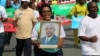 FILE - A woman holds up a picture of Burundi's President Pierre Nkurunziza during a rally in Bujumbura on May 14, 2016, commemorating the one-year anniversary of the failed attempt of a government coup. Authorities in Burundi arrested 11 students last week for defacing a photo of President Pierre Nkurunziza.
