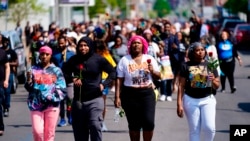 Des gens marchent sur les lieux d'une fusillade dans un supermarché de Buffalo, N.Y., le 15 mai 2022.