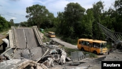 Un convoi d'évacuation parti de la ville de Kupiansk, longe une route endommagée à la périphérie de Kharkiv, en Ukraine, le 30 mai 2022.