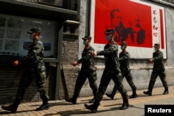 資料照：中國武警士兵走過北京街頭一幅馬克思恩格斯畫像及寫有“不忘初心”的宣傳畫。 （2020年5月22日）